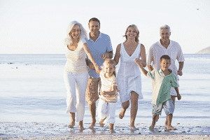 family walking on the beach, smiling and laughing, enjoying their multi family vacation